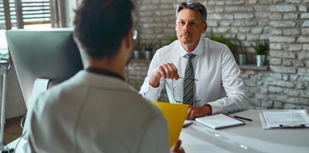Man sits in front of another man across a table during a job interview.